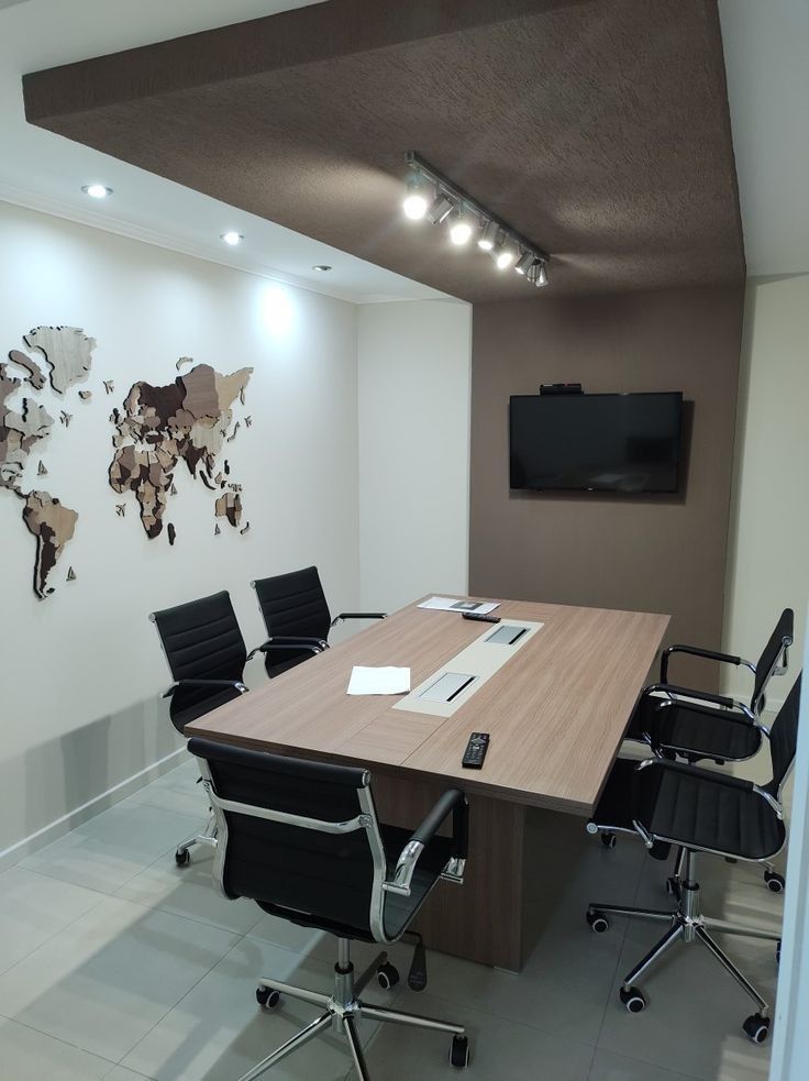 A modern co working meeting room featuring a professional conference table, ergonomic chairs, a wall-mounted display, and a decorative world map accent wall.